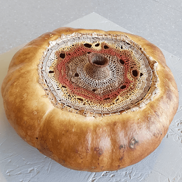 A pumpkin embellished with an intricate crocheted center